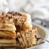 Fork filled with a bite a chocolate chip pancakes.