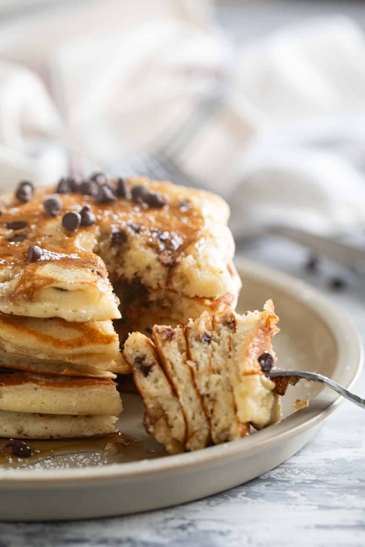 Fork filled with a bite a chocolate chip pancakes.