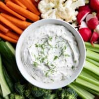 Bowl filled with dill dip, surrounded by assorted vegetables.