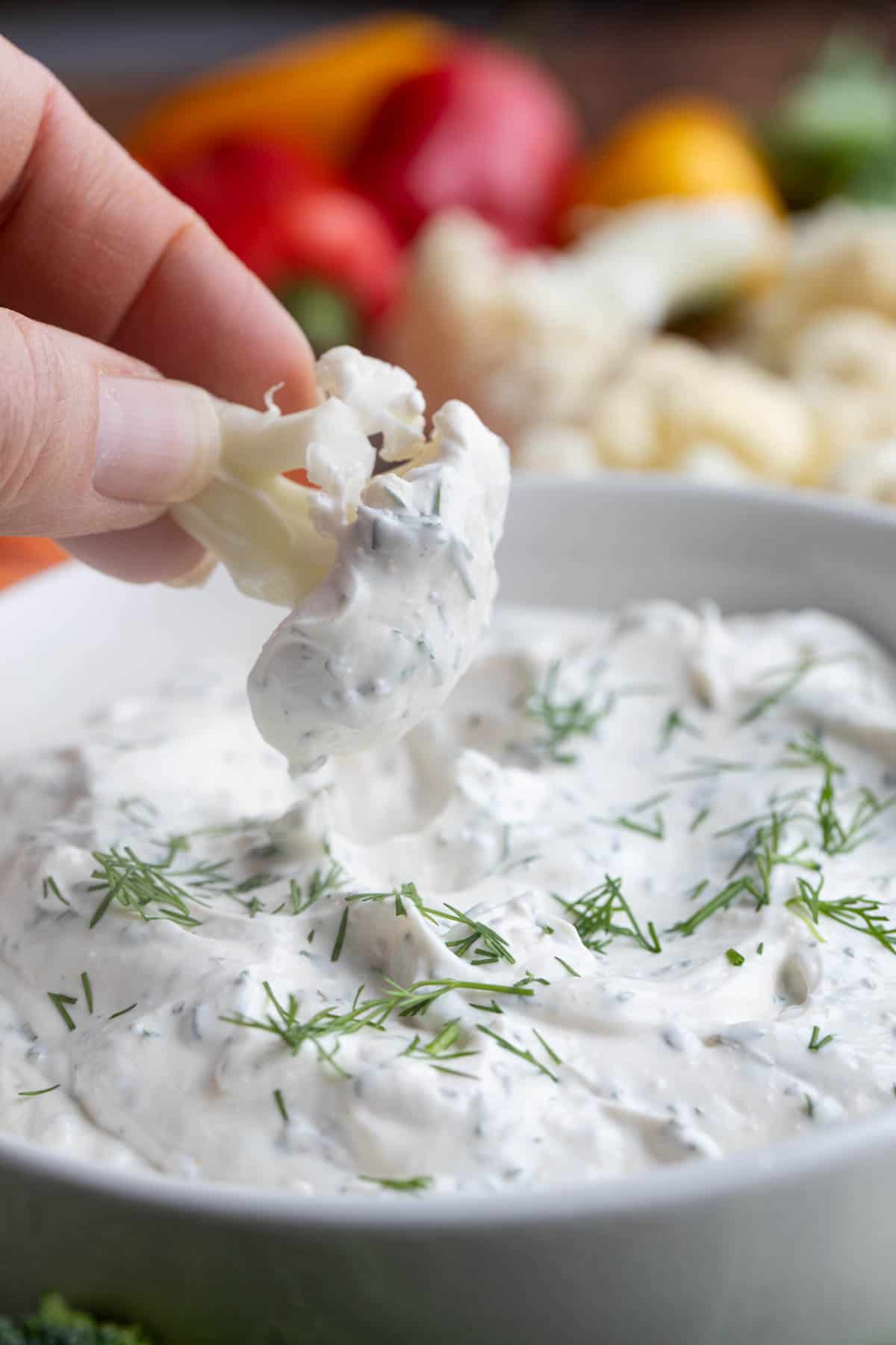 Piece of cauliflower being dipped into Dill Dip.