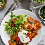 Ground beef enchiladas topped with sour cream tomatoes, and cilantro.