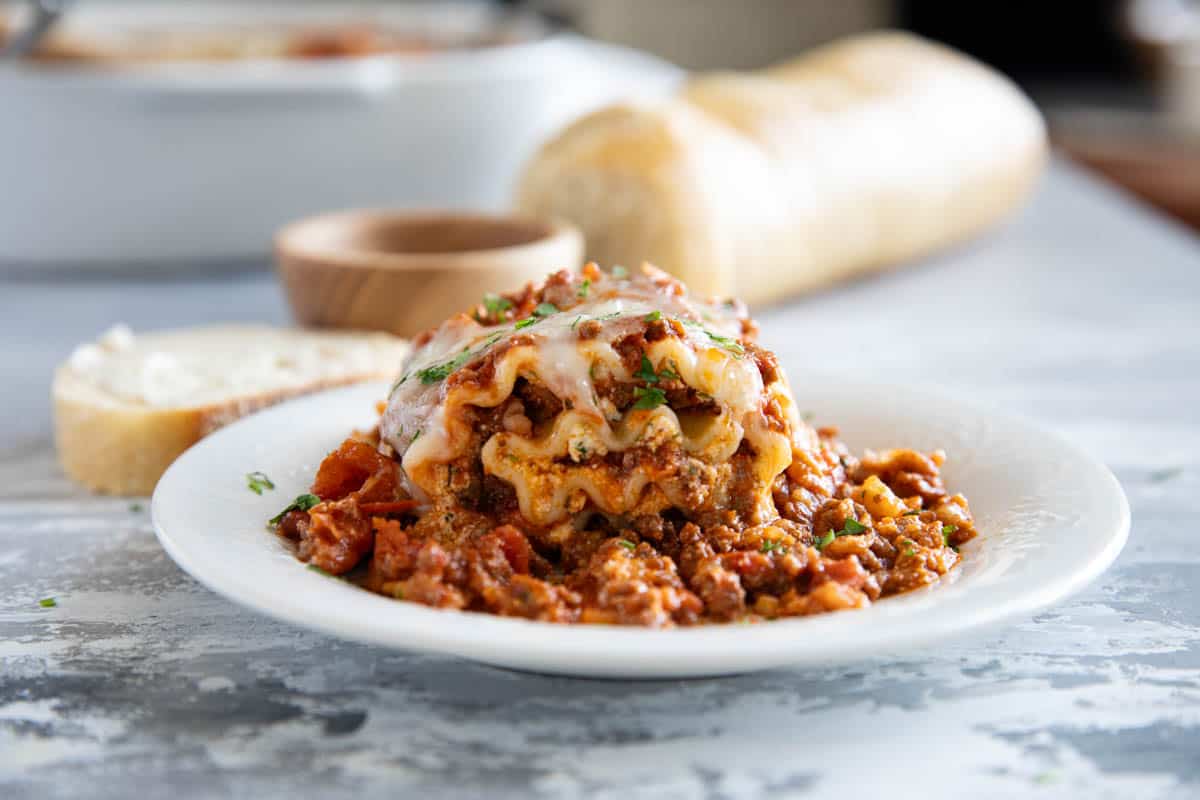 Plate with lasagna roll ups with bread in the background.