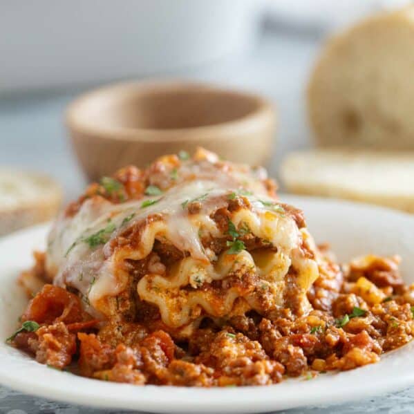 Single Lasagna Roll Up on a plate with parsley sprinkled on top.