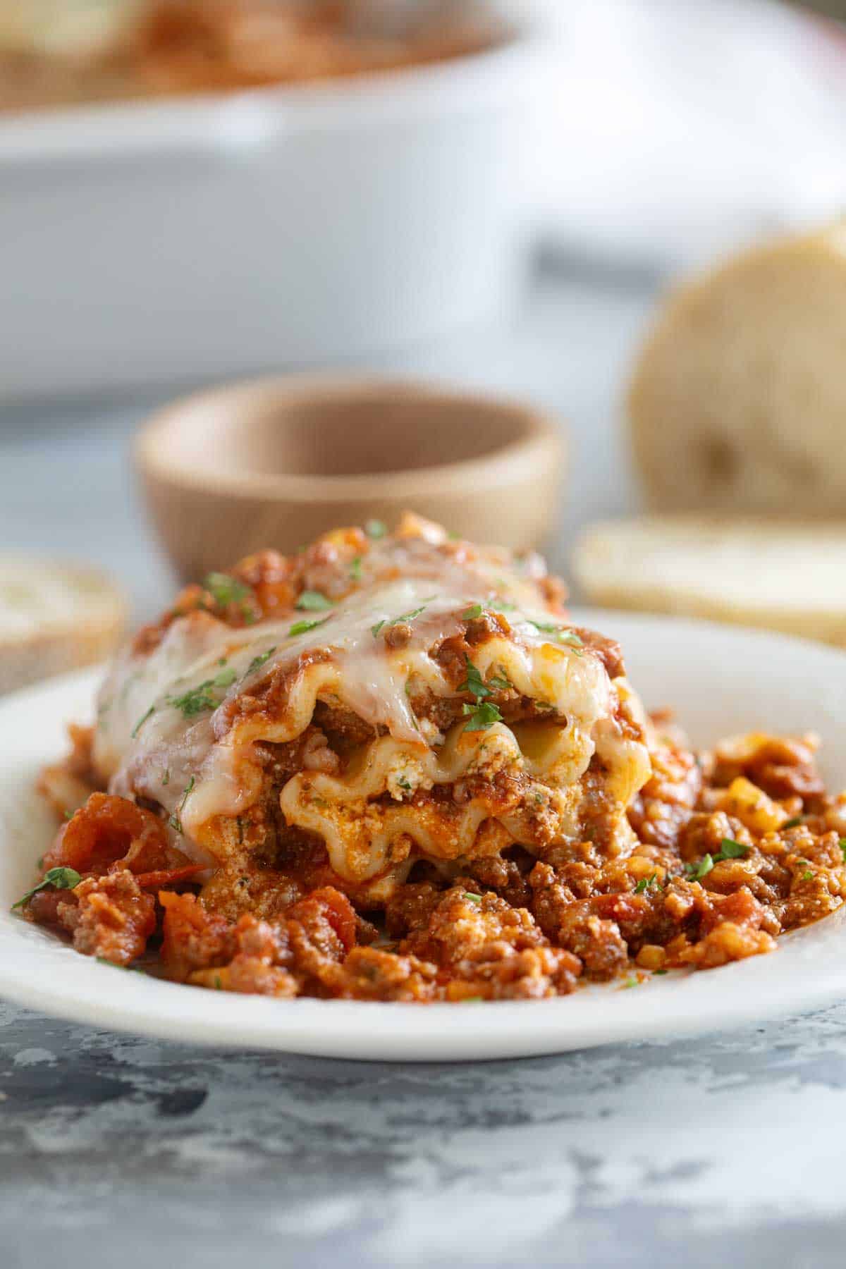 Single Lasagna Roll Up on a plate with parsley sprinkled on top.