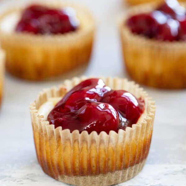 Mini Cheesecakes made in muffin tins, topped with cherries.