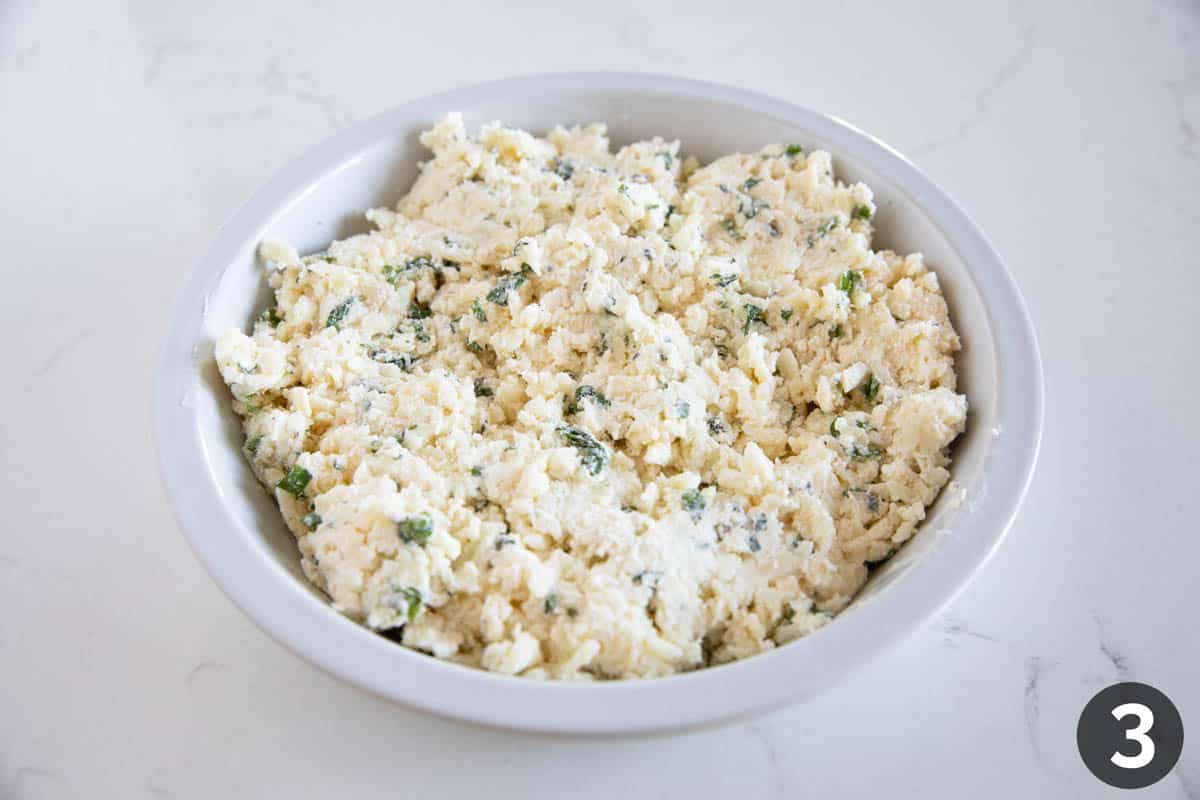 Putting white cheese dip into a pie plate.