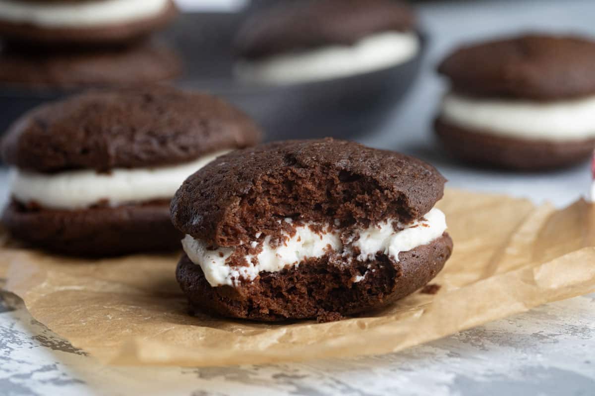 Whoopie Pies on parchment paper, with a bite taken from one.