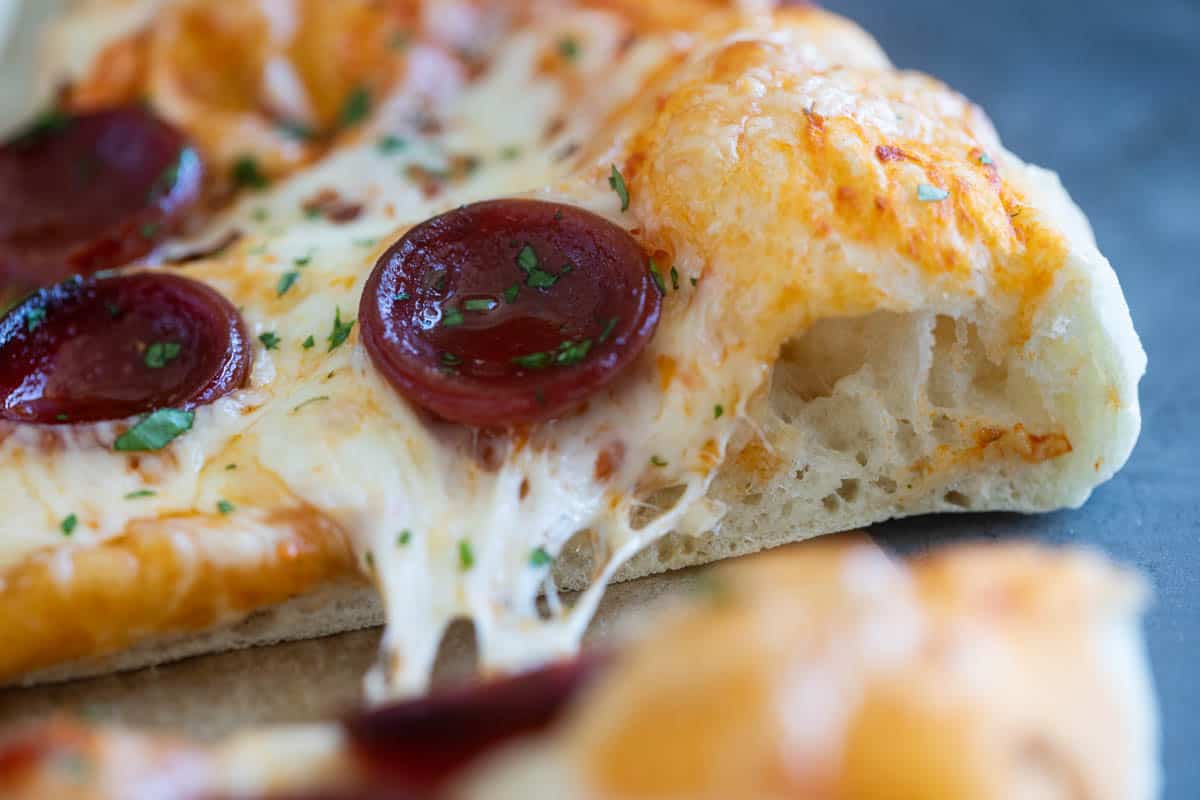 Slice of pizza made with artisan pizza dough showing interior texture of dough.