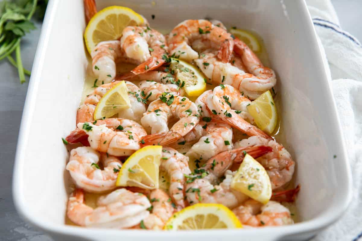 Baked shrimp in a casserole dish with lemon slices.