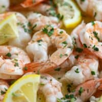 Close up of baked shrimp with lemon slices and parsley.