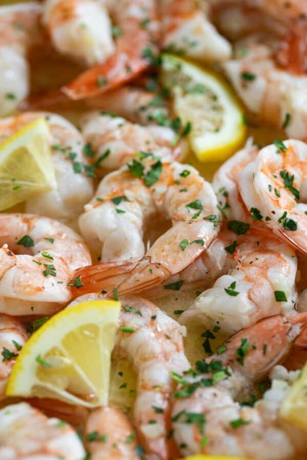 Close up of baked shrimp with lemon slices and parsley.