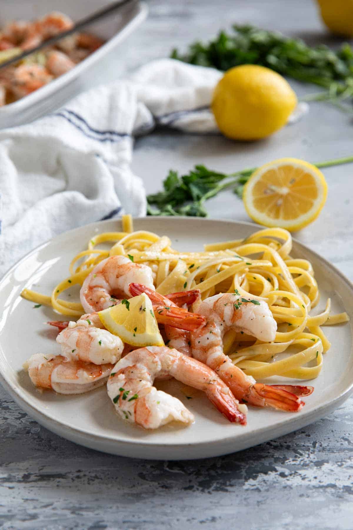 Plate with linguine, baked shrimp, and a lemon slice.