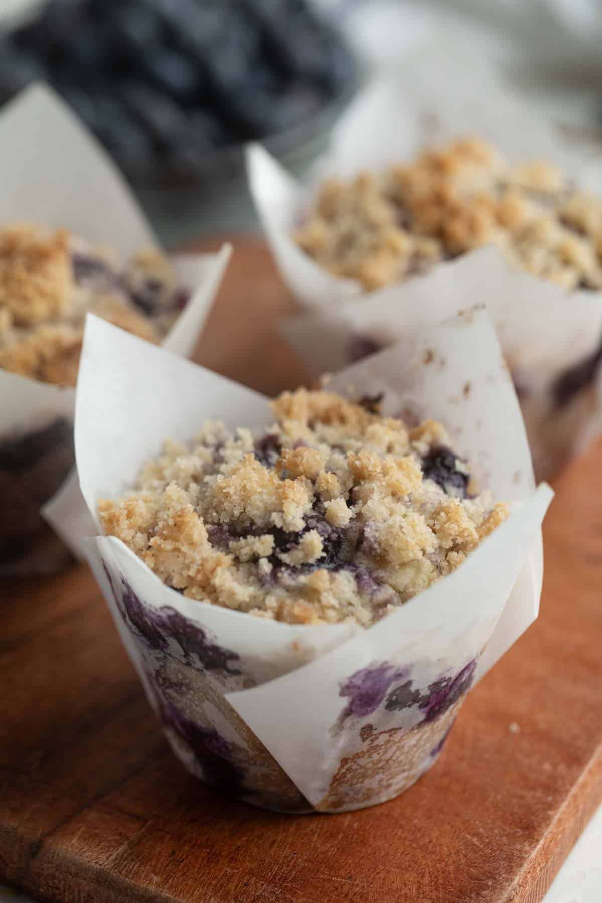 Blueberry Muffins with crumb topping on a wooden board.