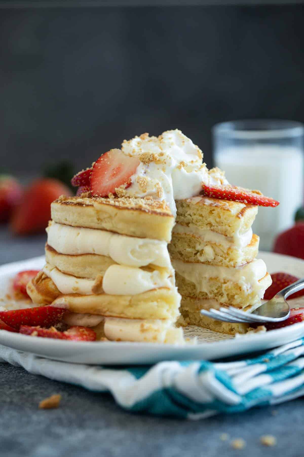 Stack of cheesecake pancakes with a bite taken from them.