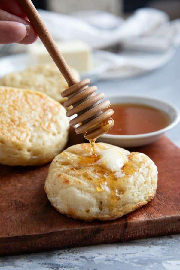Drizzling honey onto crumpets.