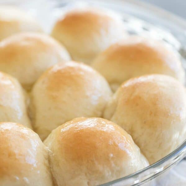 Dinner rolls with butter on top in a round dish.