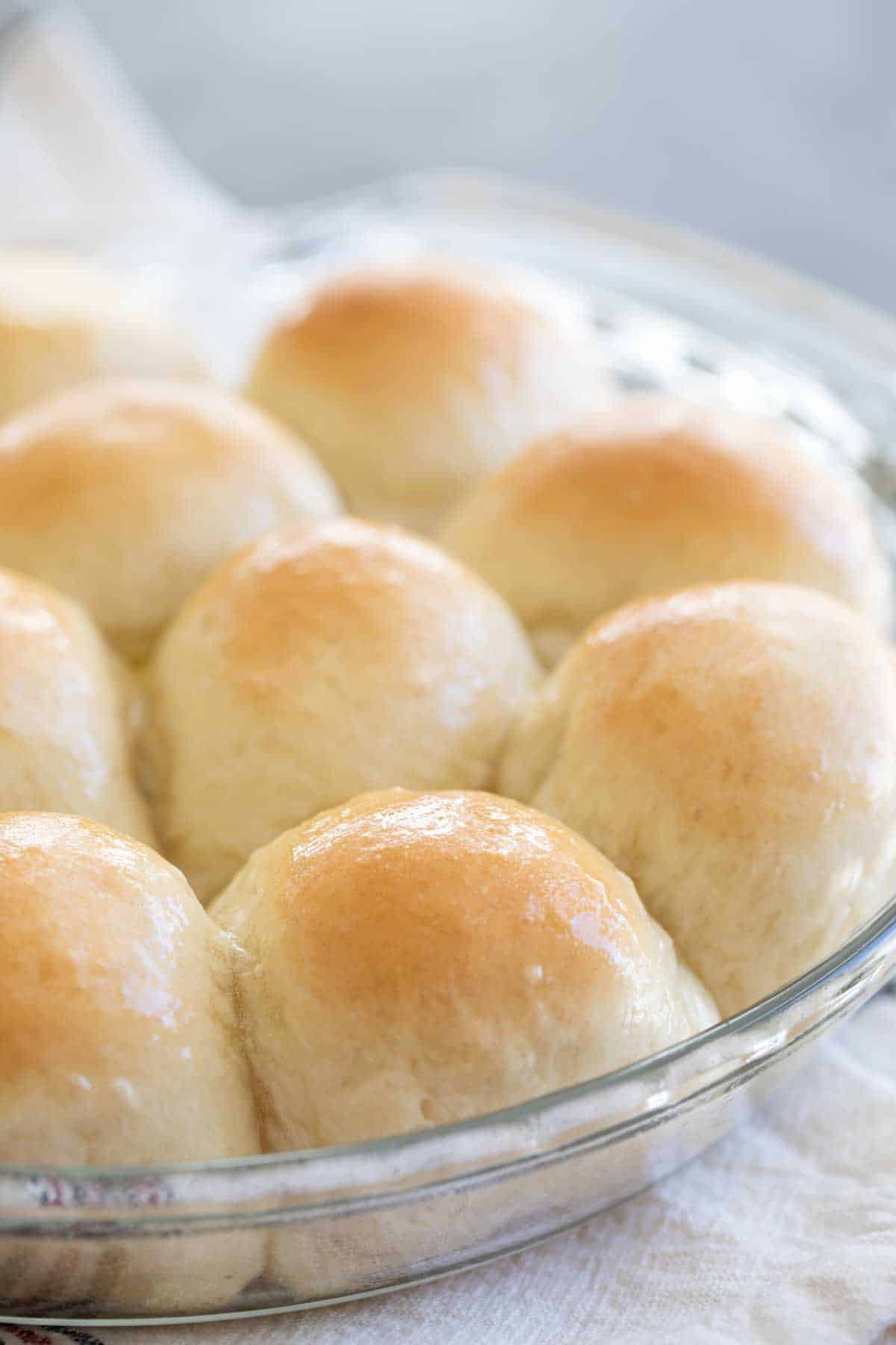 Dinner rolls with butter on top in a round dish.