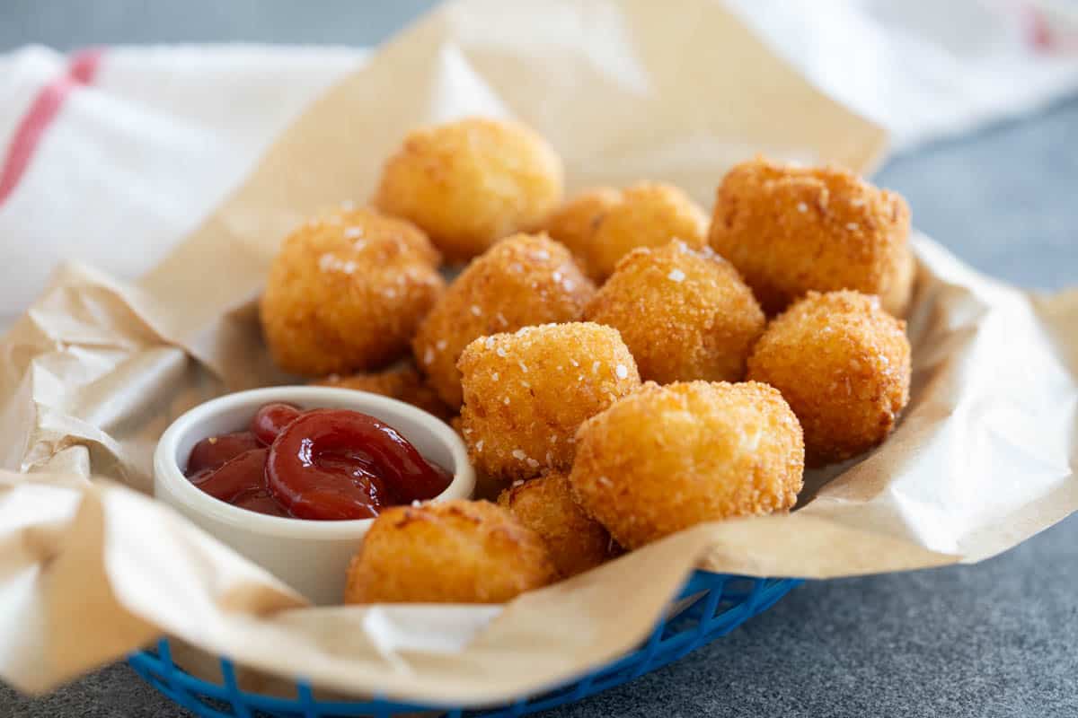 Basket filled with homemade tater tots and a small ramekin of ketchup.