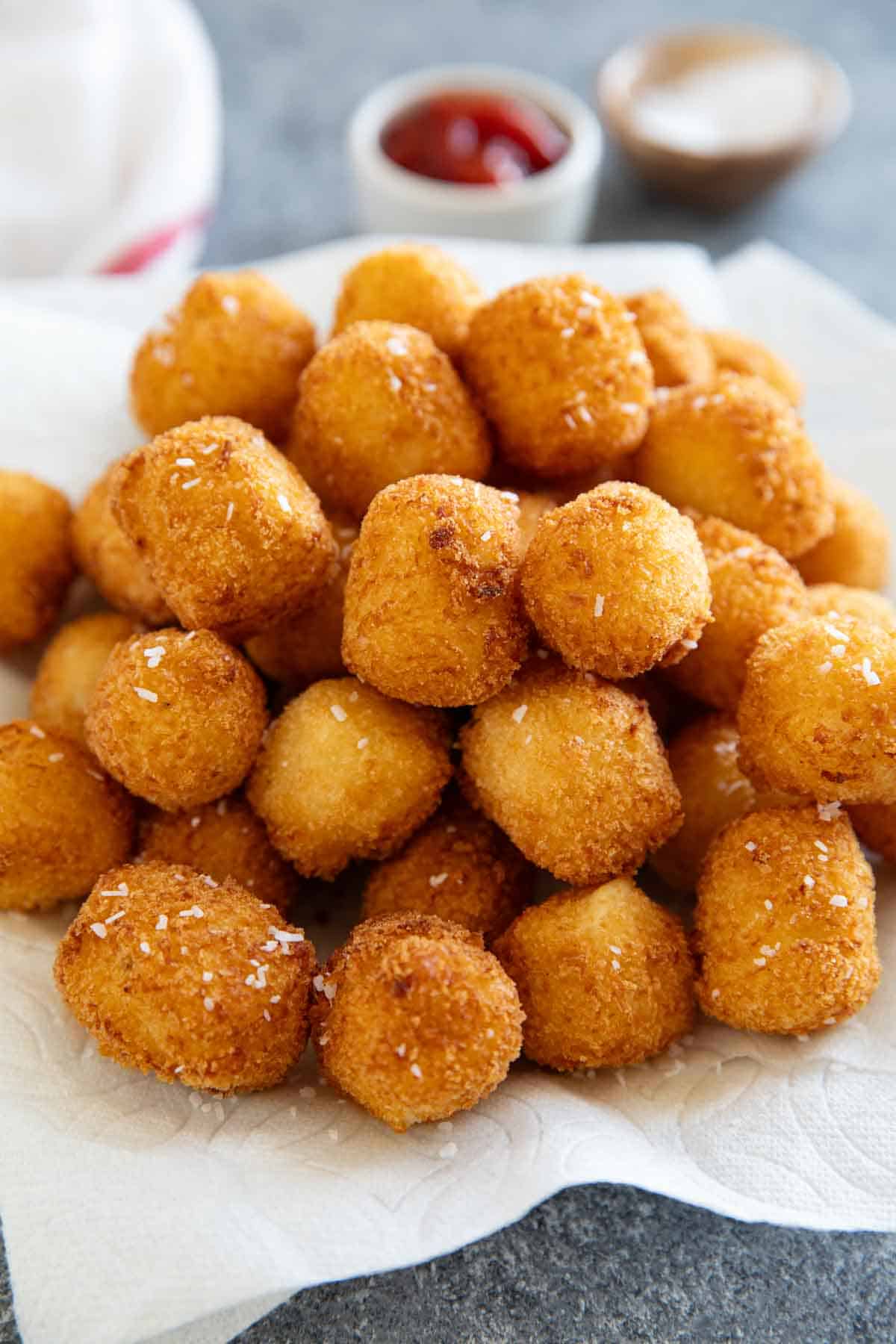Freshly fried tater tots on paper towel lined plate.