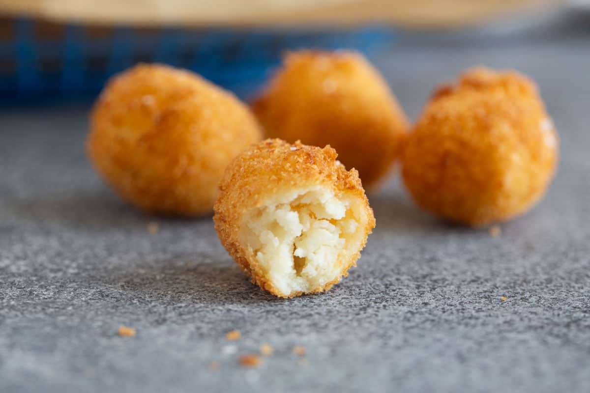 Homemade tater tots with one in half to show inside texture.