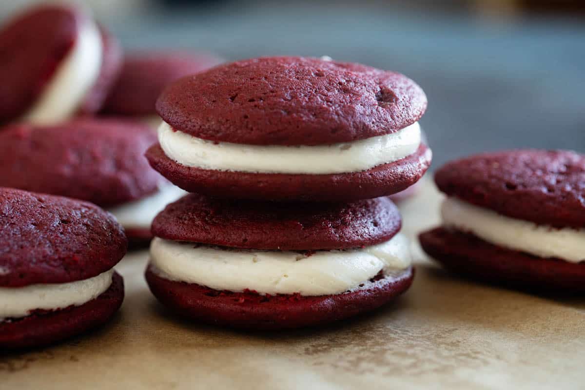 Red Velvet Whoopie Pies on parchment with two stacked on top of each other.