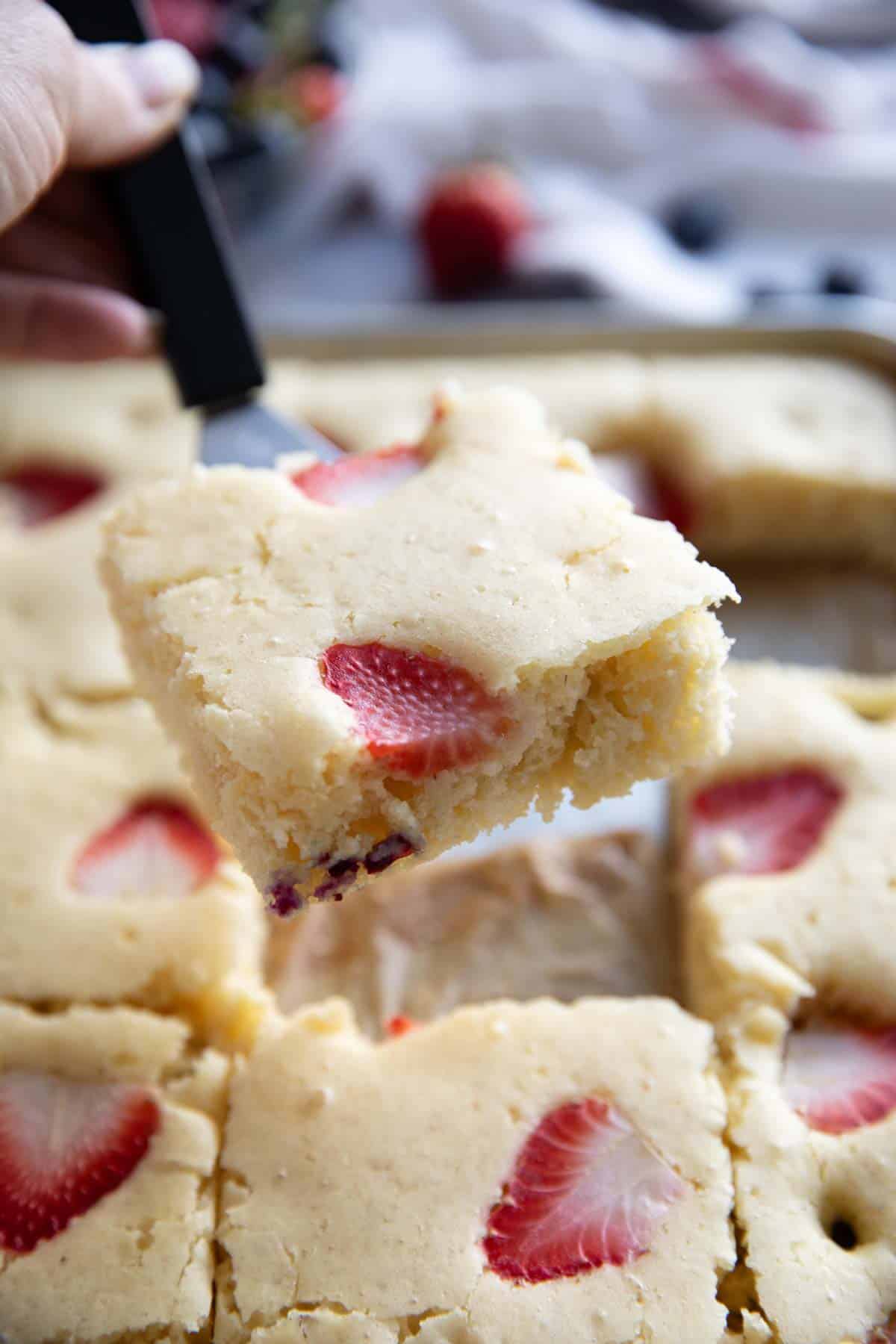 Slice of sheet pan pancakes being taken from pan with a small spatula.