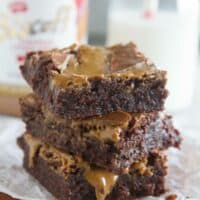 Stack of Biscoff Brownies with a jar of Biscoff spread in the background.