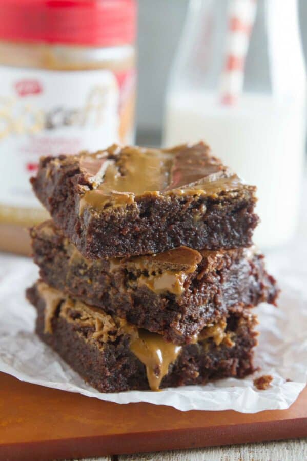 Stack of Biscoff Brownies with a jar of Biscoff spread in the background.