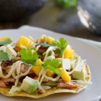 Tostada topped with blackened salmon, mangoes, avocado, and a creamy sauce.