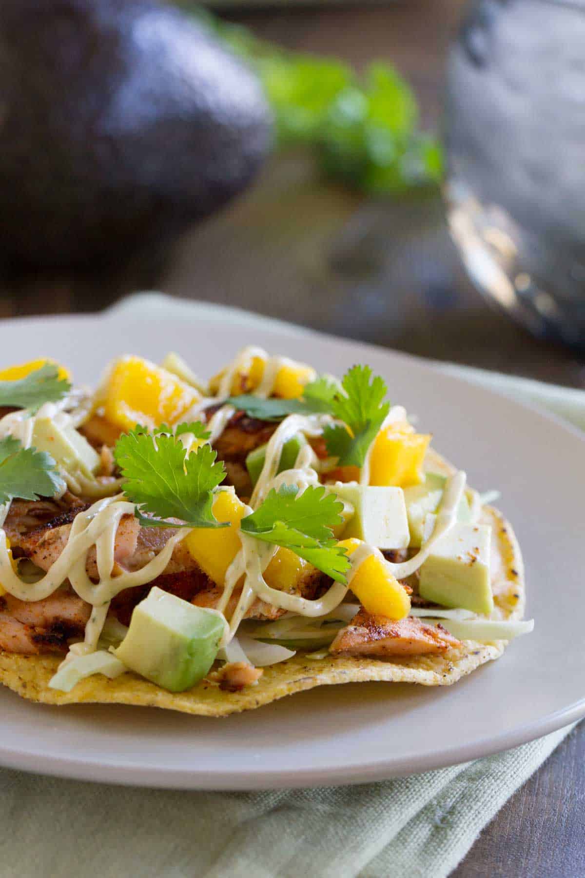 Tostada topped with blackened salmon, mangoes, avocado, and a creamy sauce.