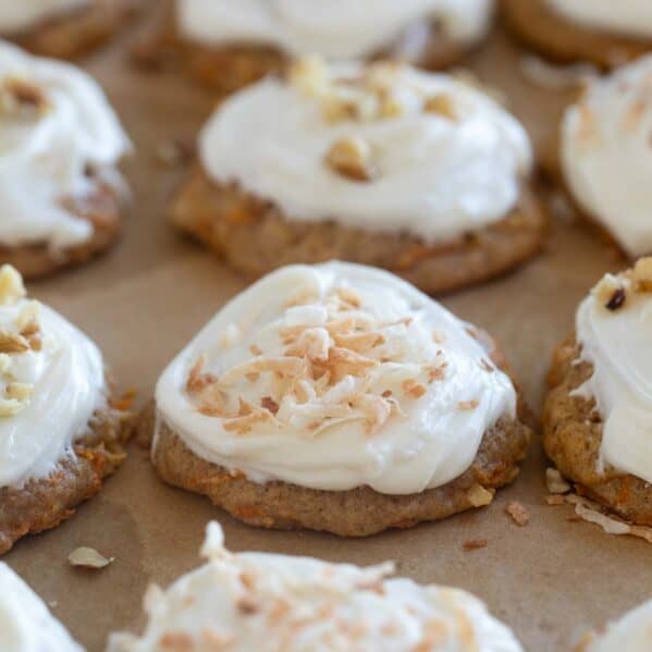 Carrot Cake Cookies topped with coconut and walnuts on a baking sheet.