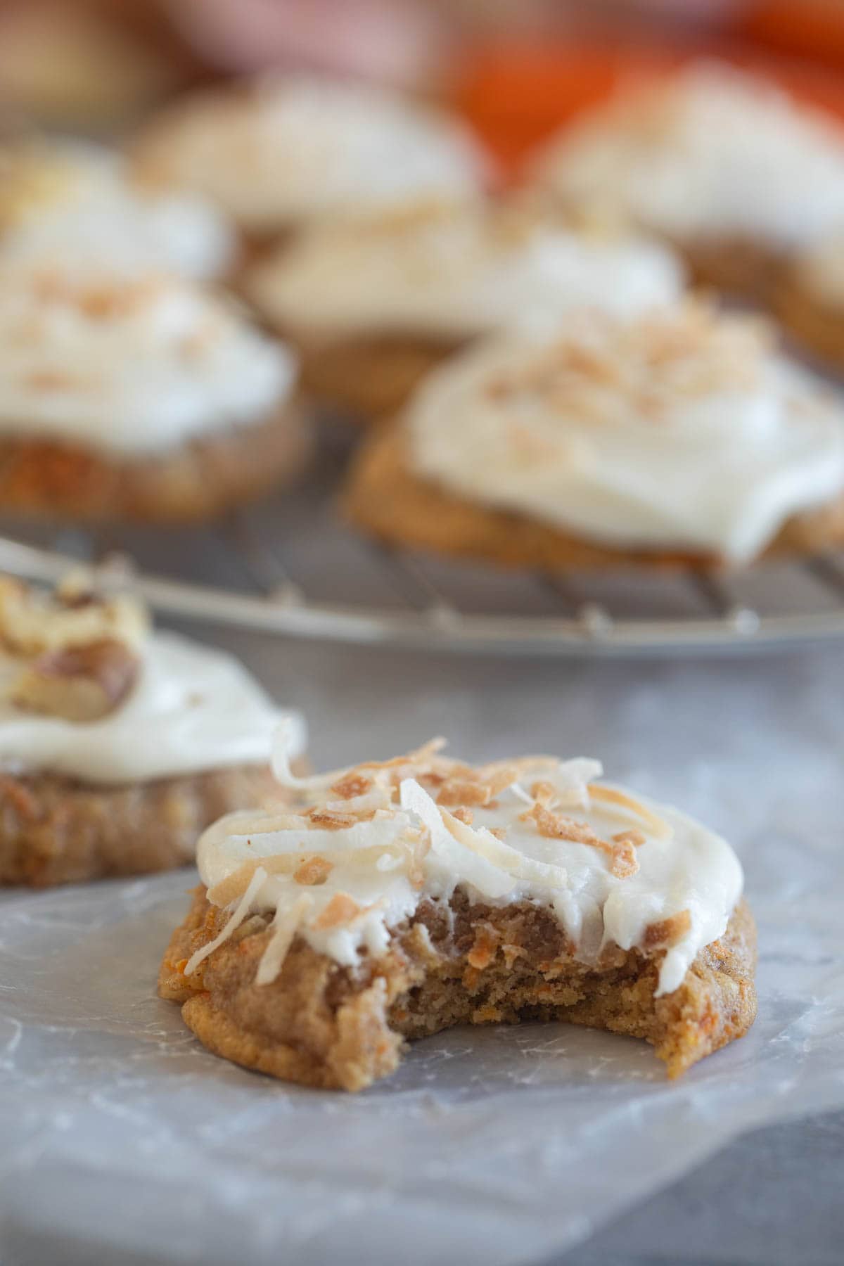 Carrot Cake Cookies with cream cheese frosting with a bite taken from one cookie.