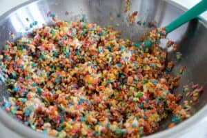 Mixing ingredients together for Fruity Pebble Rice Crispy Treats.