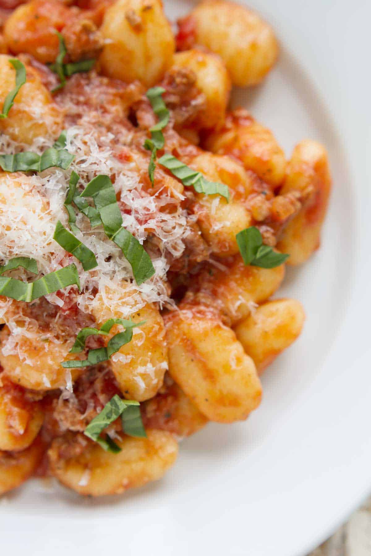 Gnocchi topped with a meat sauce, parmesan, and basil.