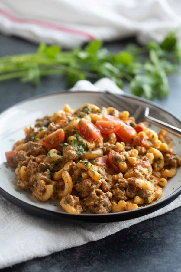 Plate filled with taco Mac and cheese topped with tomatoes and cilantro.