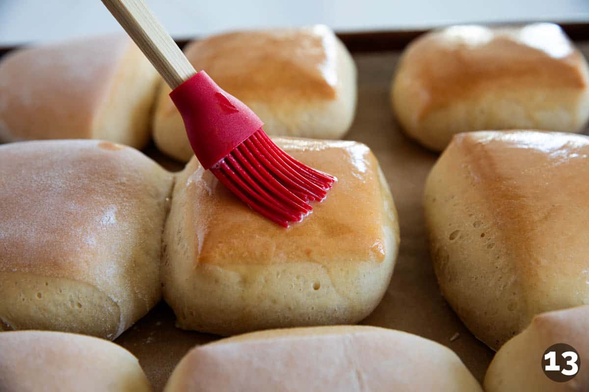Brushing butter on top of baked Texas Roadhouse Rolls.