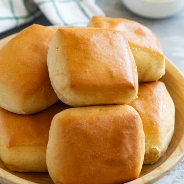 Texas Roadhouse Rolls stacked in a wooden bowl.