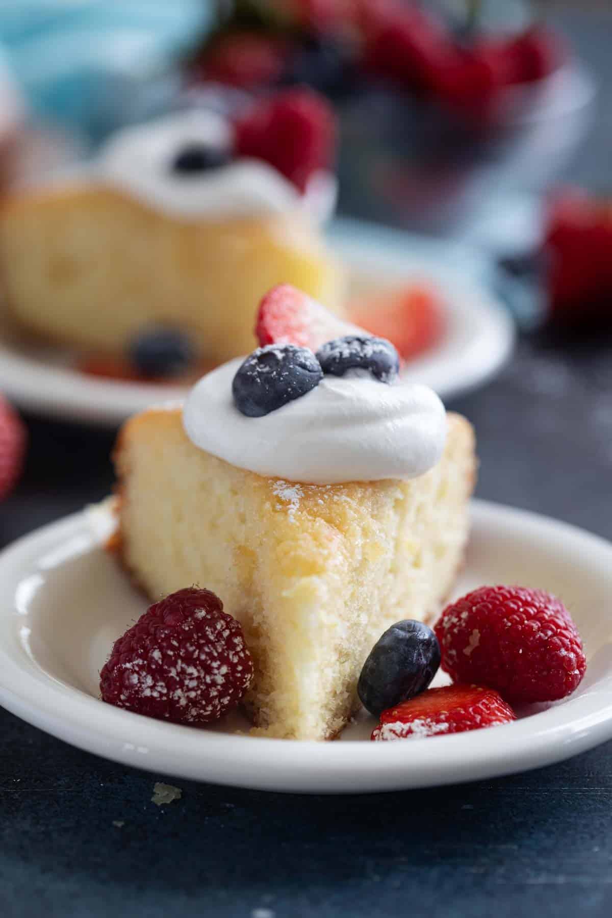 Slice of yogurt cake topped with whipped cream and berries.