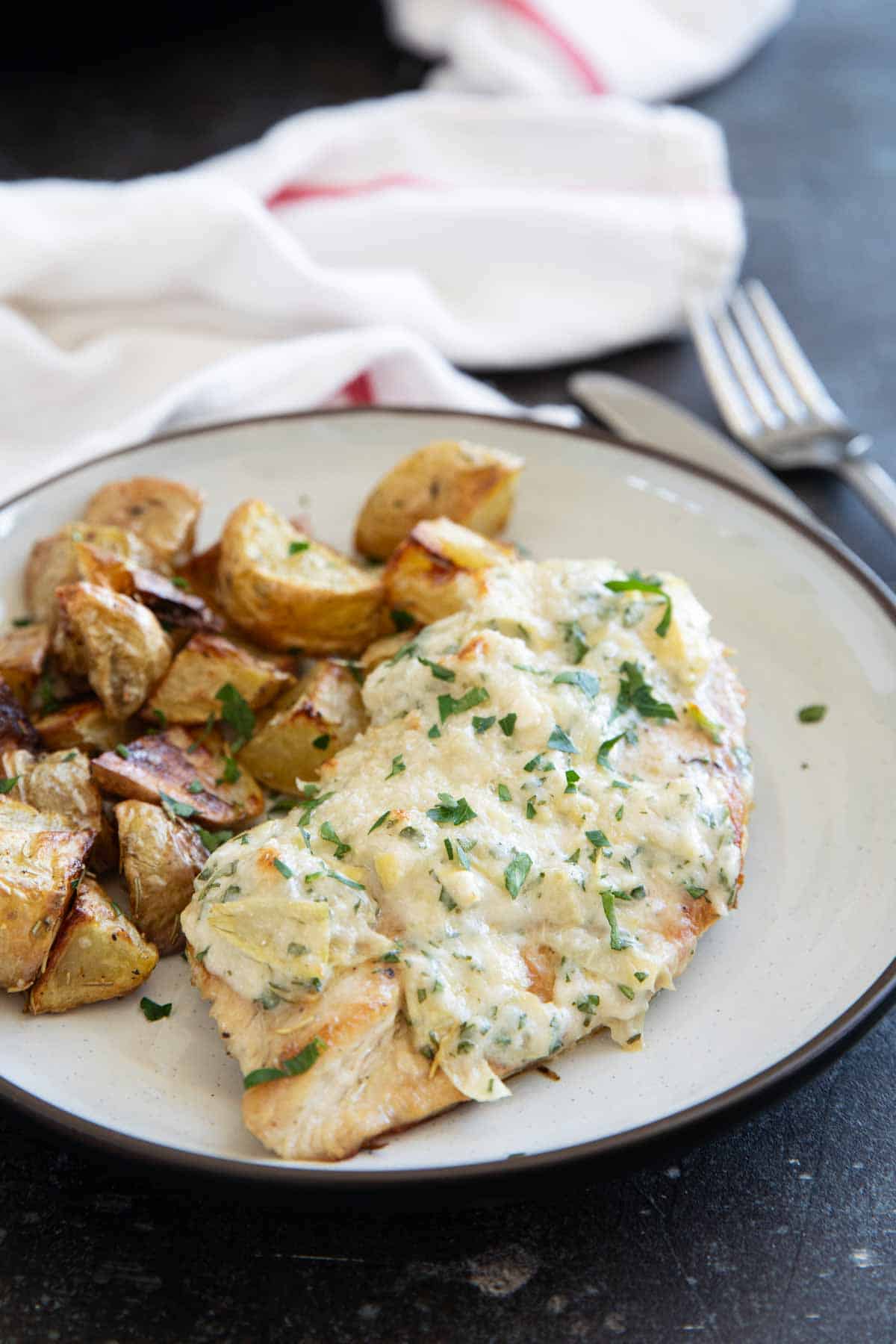 Artichoke Chicken on a plate with roasted potatoes.