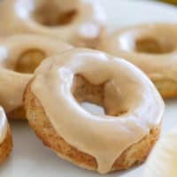 Baked banana donuts on a white plate, frosted with peanut butter icing.