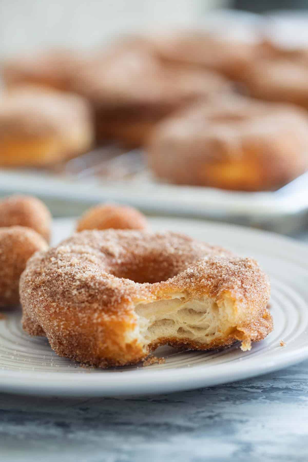 Cinnamon sugar biscuit donut on a plate with a bite taken from it.