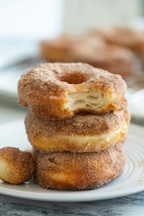 Three biscuit donuts stacked on top of each other, covered in cinnamon sugar.
