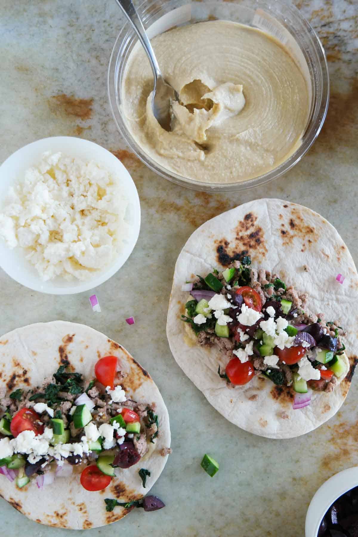Greek tacos with spinach, feta, hummus, and ground turkey.