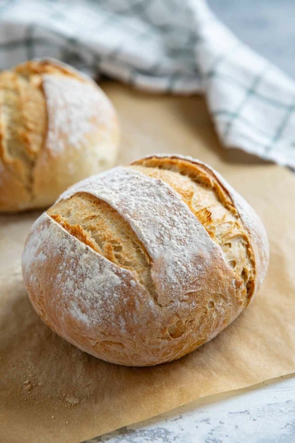 Two loaves of artisan bread on parchment paper.