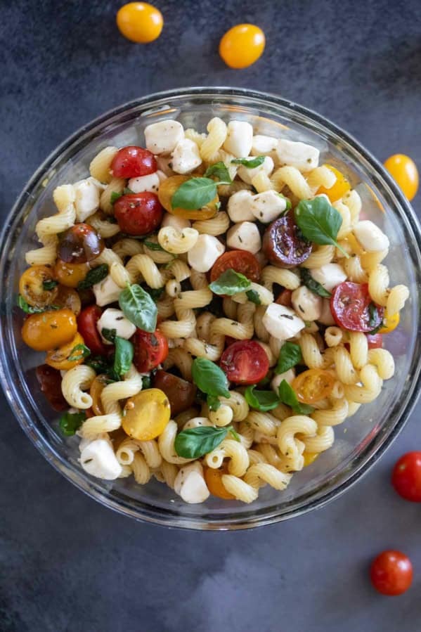 Bowl filled with Caprese Pasta Salad with pasta, tomatoes, mozzarella, and basil.