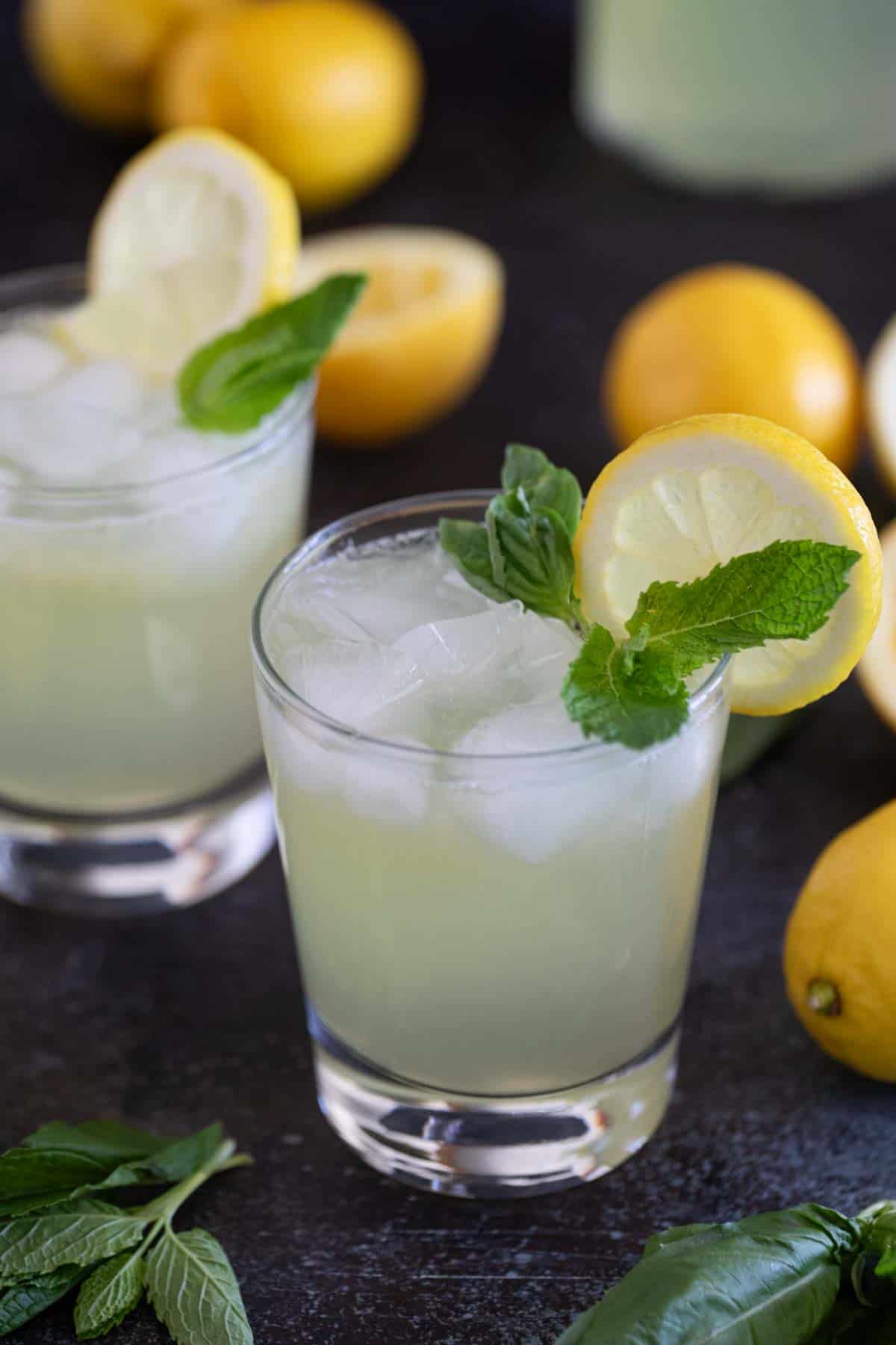 Glass of Mint and Basil Lemonade topped with fresh mint and basil.