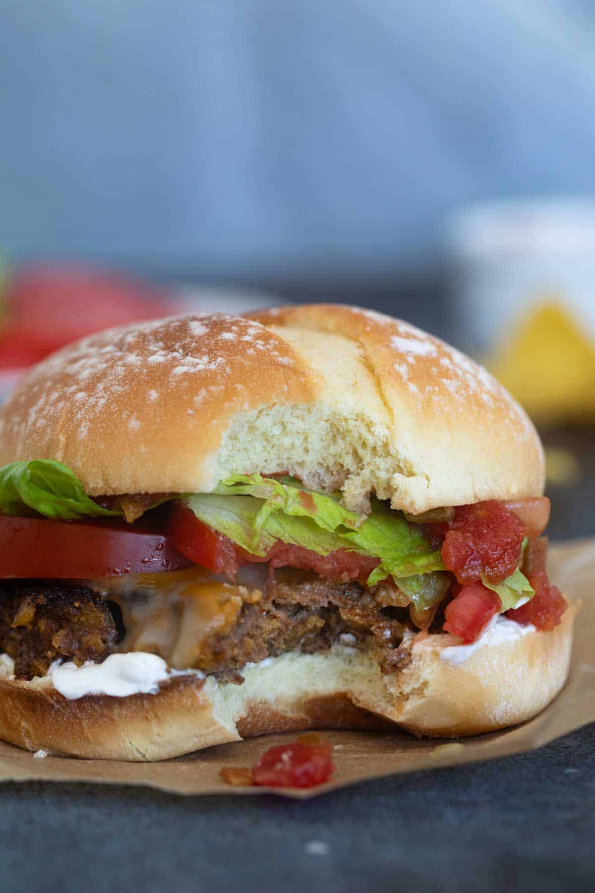 Taco burger with a bite taken from it.