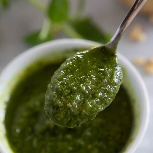 Spoonful of fresh basil pesto over a bowl.