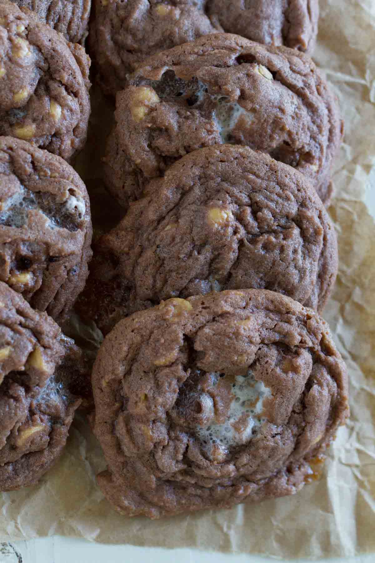 Chocolate, Peanut Butter, and Marshmallow Pudding Cookies laid down on parchment next to each other.