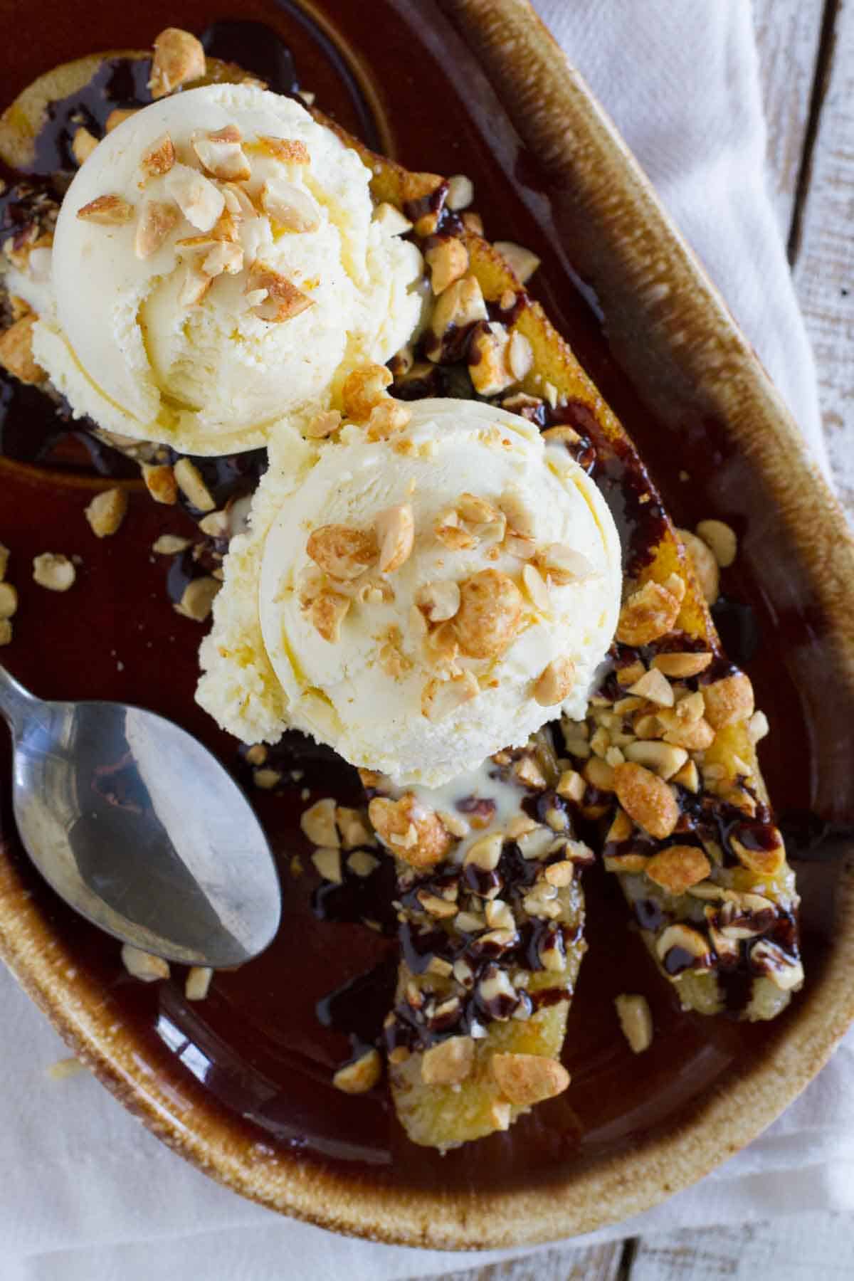 Pan fried banana split topped with ice cream and peanuts.